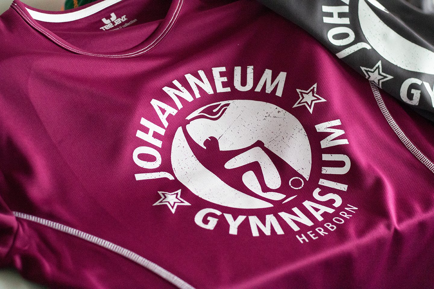 Schul-Sportshirts in Beere und Schwarz mit bedrucktem Gymnasiumslogo